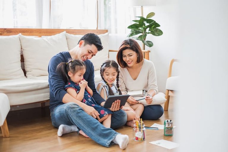 Personal-Insurance-Family-Laughing-and-Having-Fun-Watching-Movie-on-Tablet-While-Sitting-on-Floor-of-Modern-Home-1